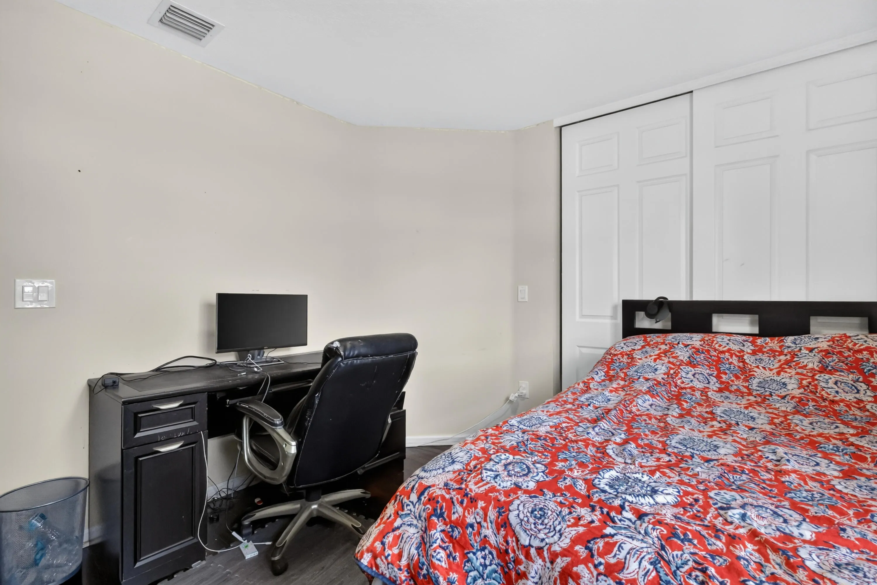 Sliding panel closet doors and dark wood-finish flooring characterize this room