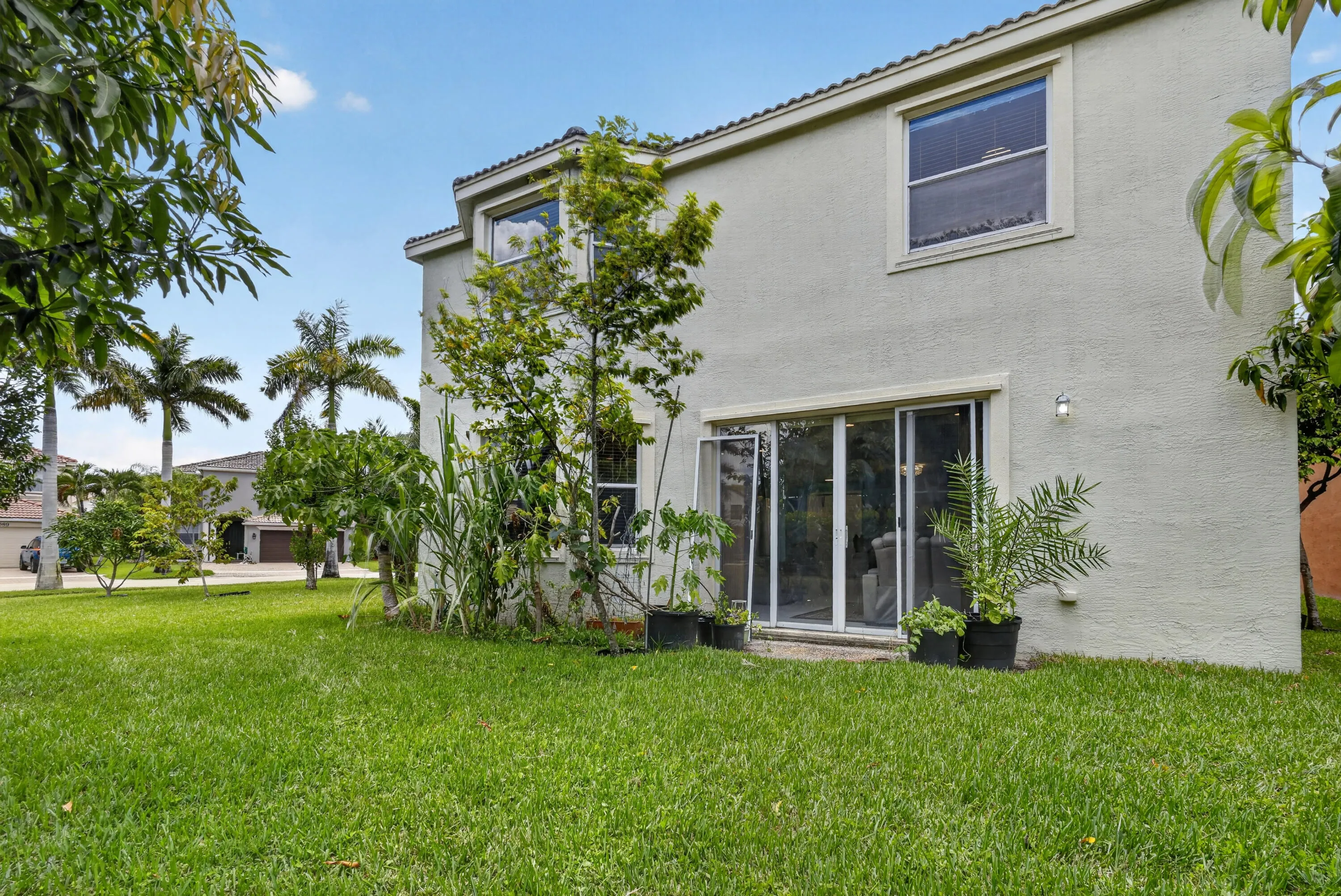 Expansive green lawn with a stucco exterior home featuring a second-story window and ground-level sliding glass doors