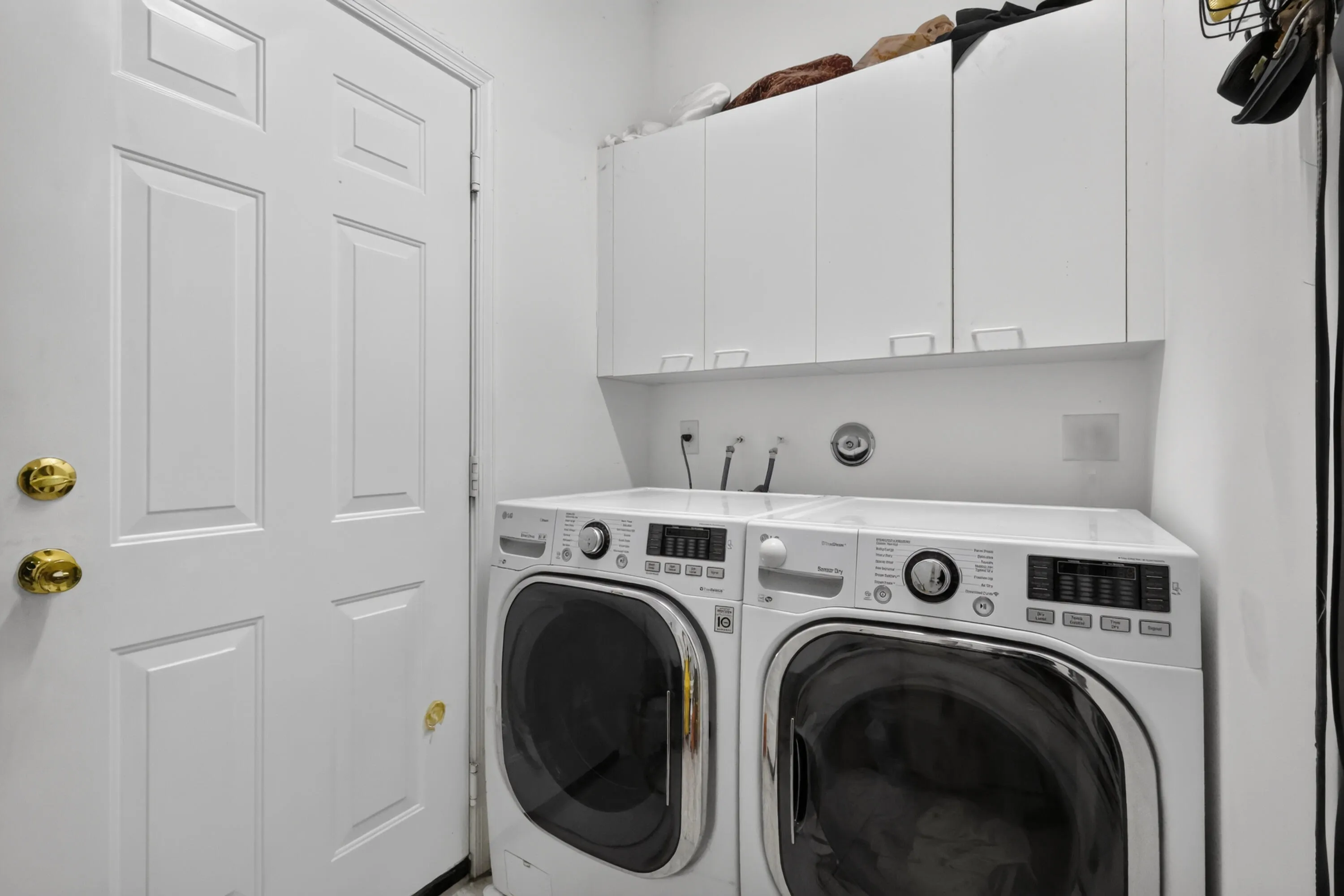 Dedicated laundry area featuring a white paneled door, built-in white cabinetry, and wall-mounted plumbing hookups