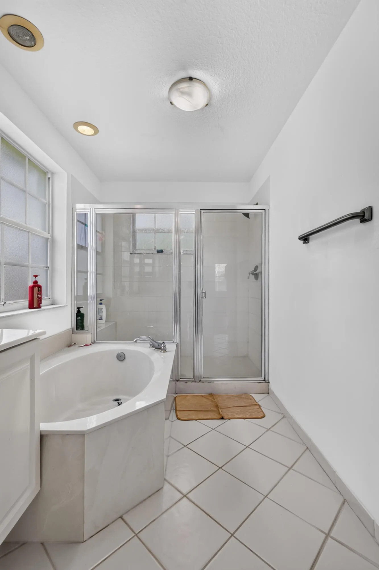 Bathroom featuring a built-in soaking tub, glass-enclosed shower, white tile flooring, recessed lighting, and a frosted glass window