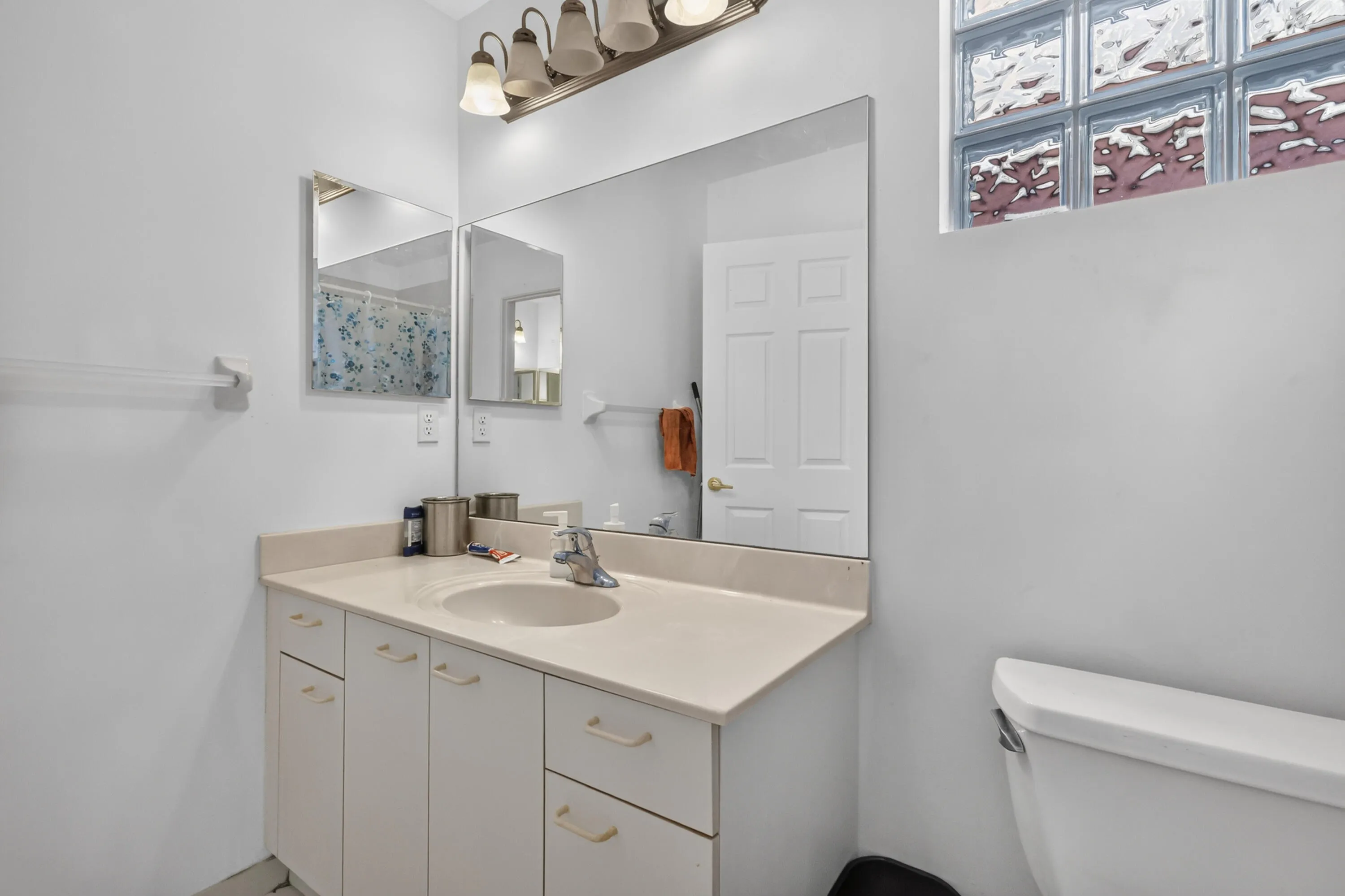 Bathroom vanity with an integrated sink, broad wall mirror, and overhead light fixture