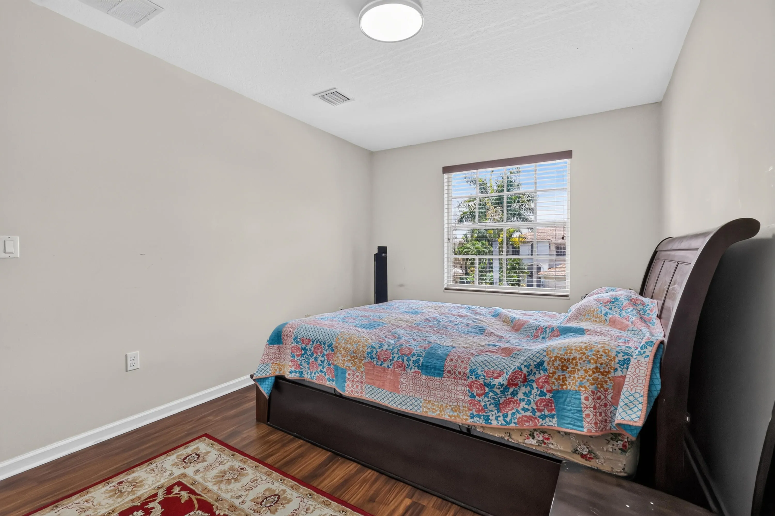 Interior room featuring wood-finish flooring, light neutral-toned walls, and a window with horizontal blinds