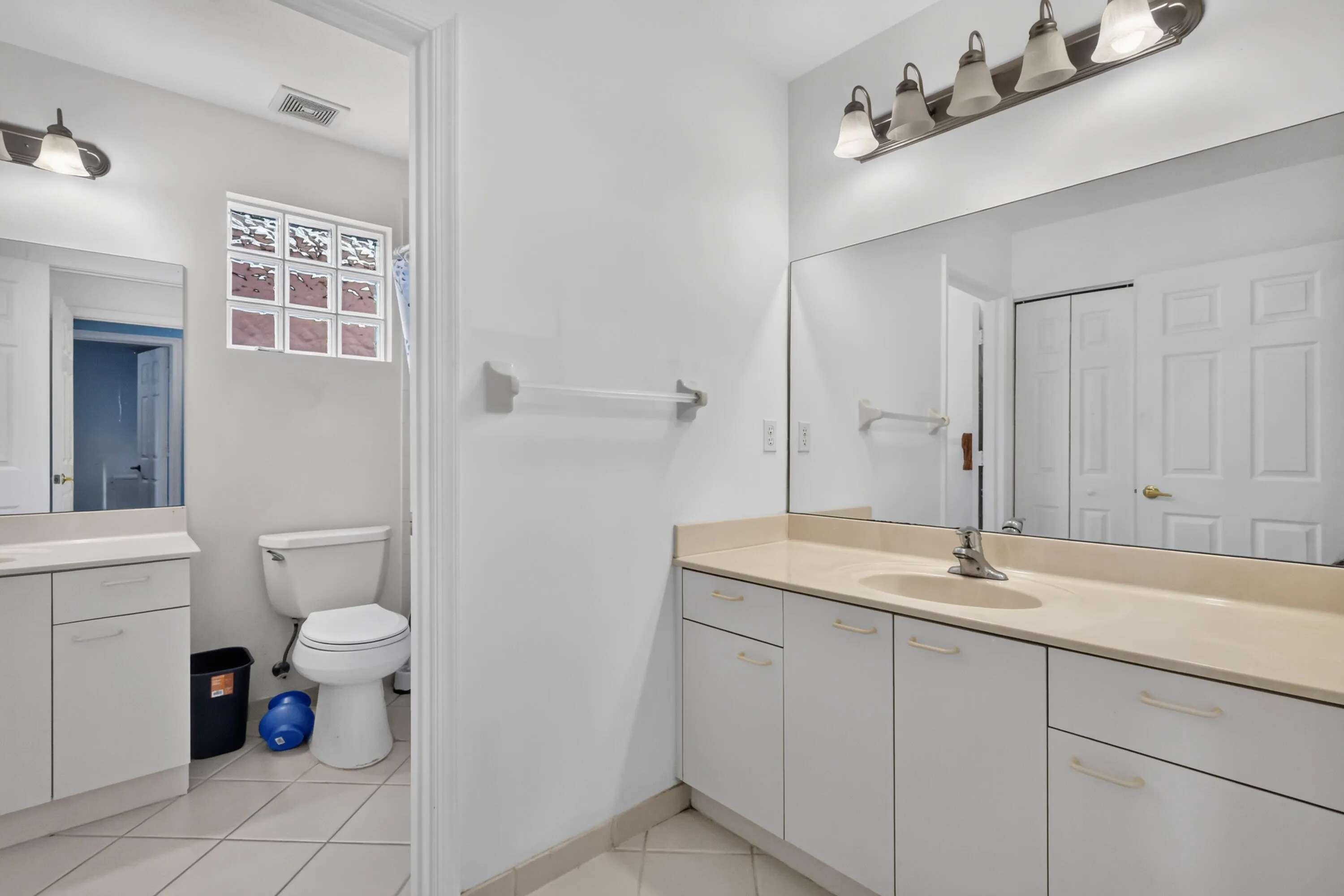 Primary bathroom featuring dual vanity with wood-finish countertop, white cabinetry with ample storage, vessel sink, and chrome fixtures