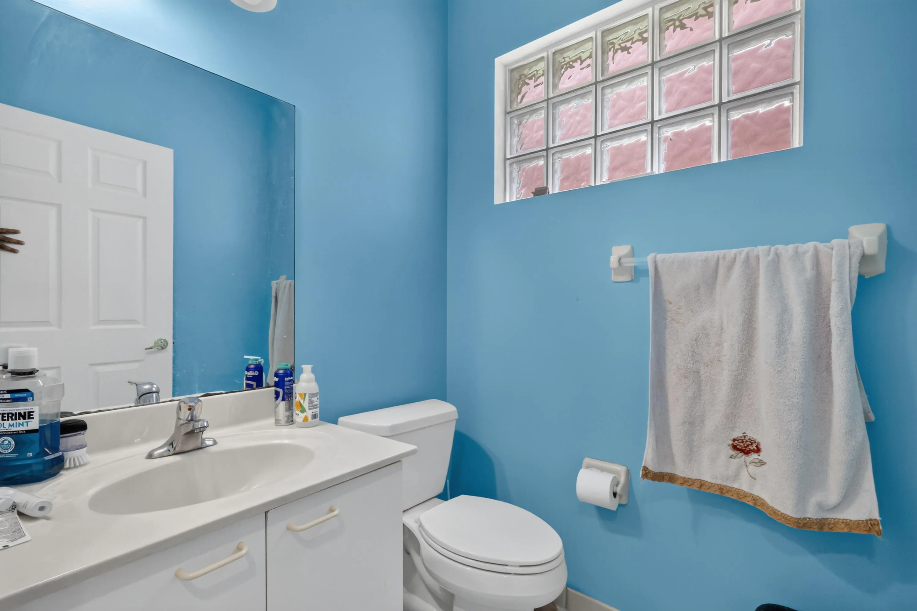 Bathroom featuring a white vanity with an integrated sink, polished chrome faucet, and a large wall mirror