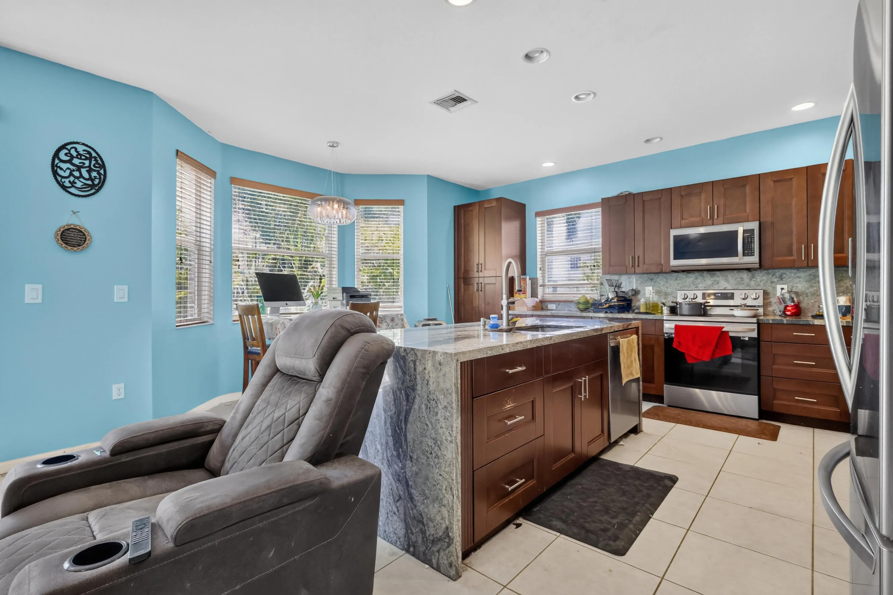 Kitchen featuring a large central island with a stone countertop, wood-finish cabinetry, stainless steel appliances, and recessed lighting