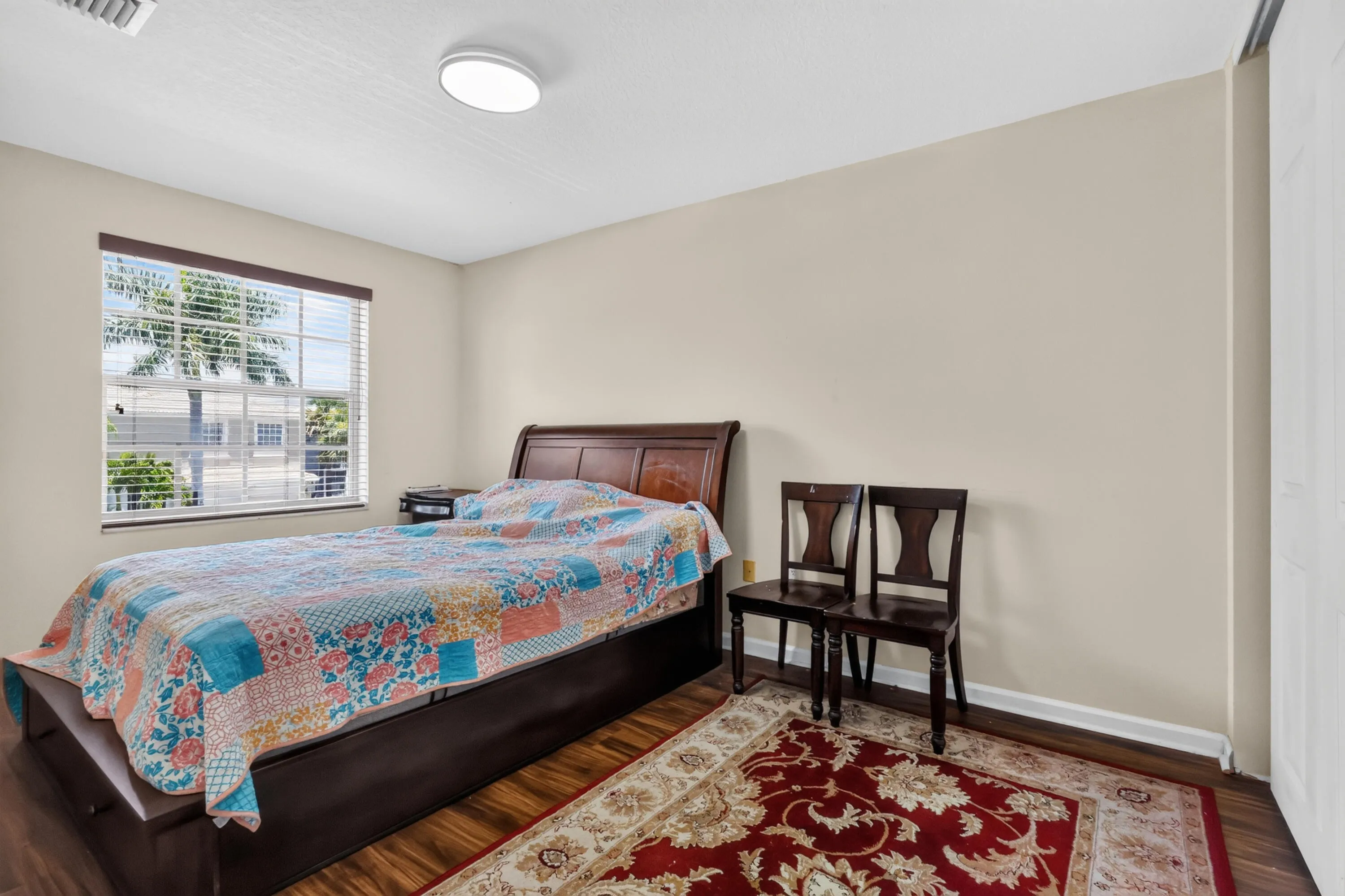 Bedroom featuring wood-finish flooring, a window with blinds, and light-toned walls