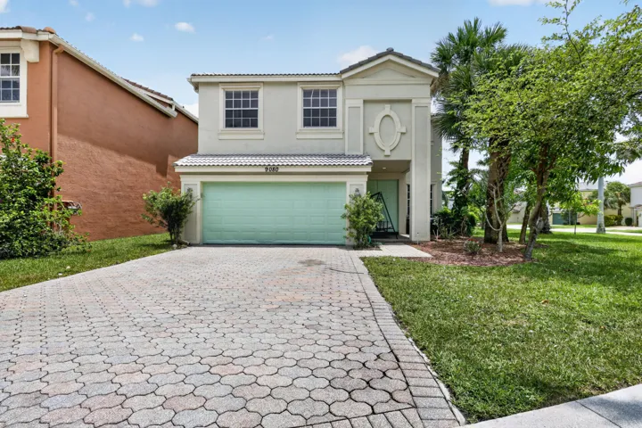 Two-story stucco residence featuring a light-colored exterior and a light green garage door