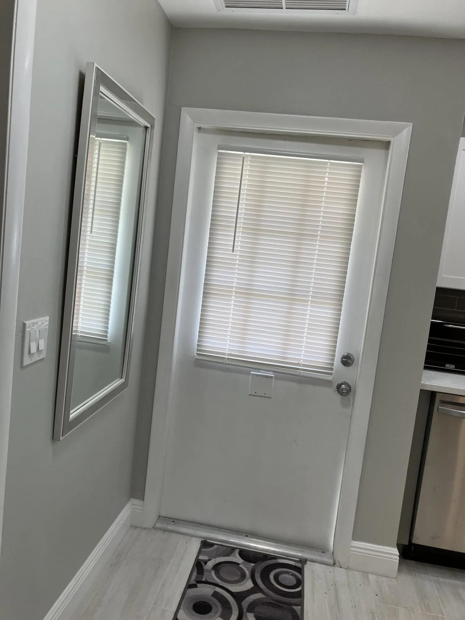 White door with integrated blinds, light gray wall color, and light wood-finish flooring