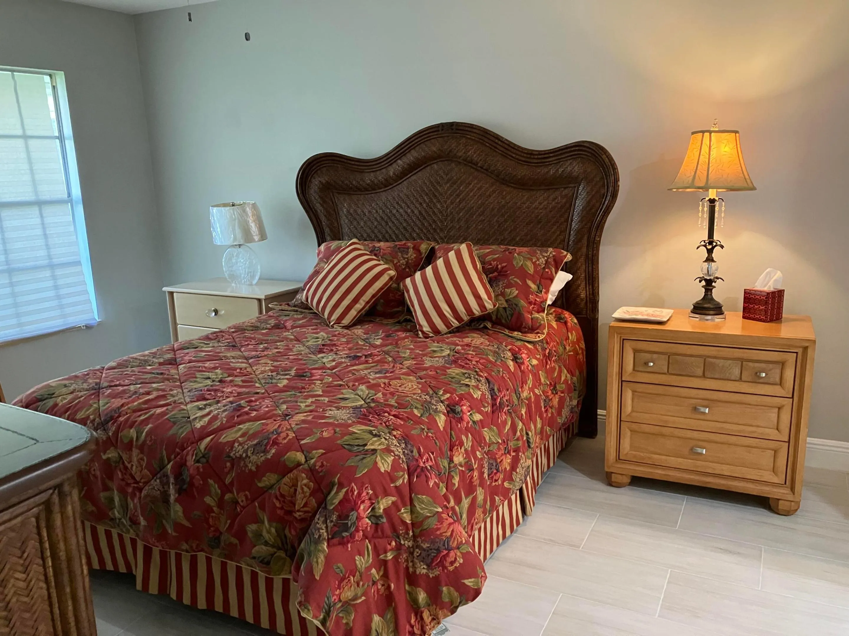 Room featuring a woven headboard, light gray wall paint, and light-toned tile flooring