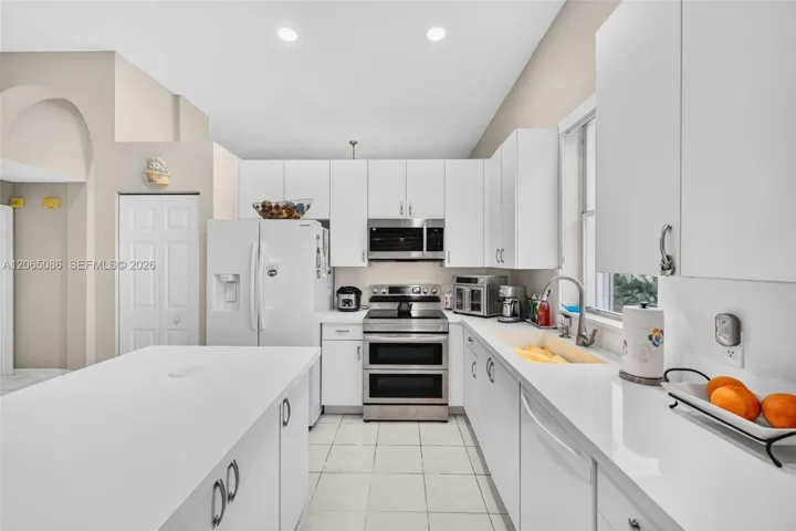 Spacious open concept kitchen w/ built in wall unit, volume ceilings and solid surface counters