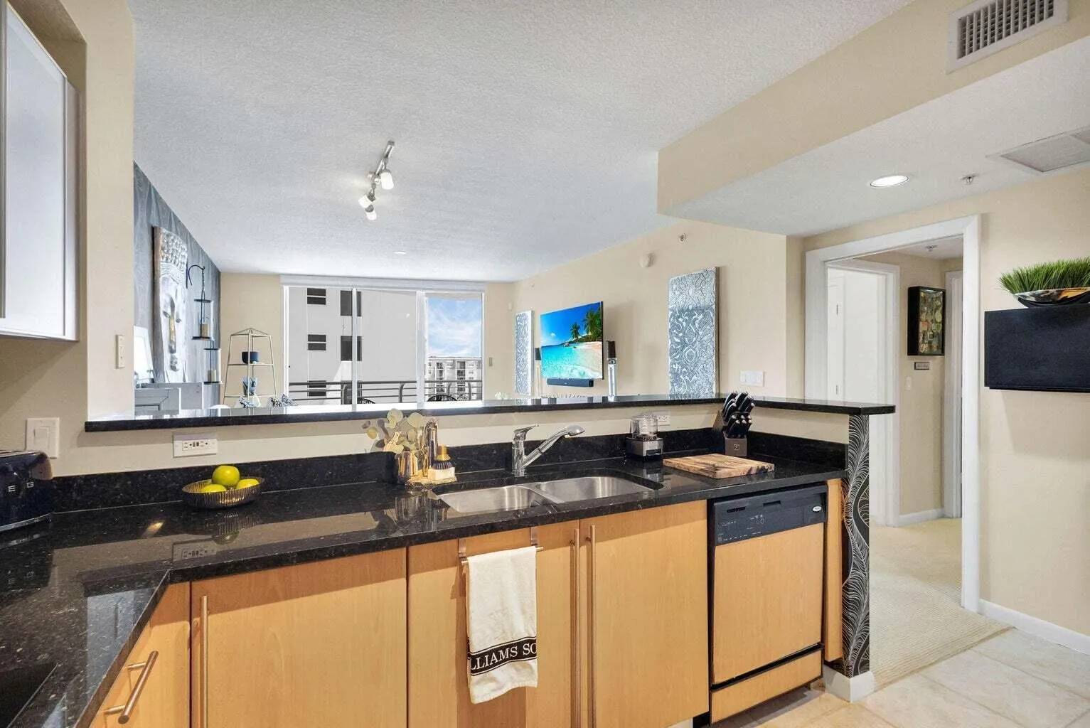 Kitchen featuring black granite countertops, wood-finish cabinetry, a stainless steel sink, and a black dishwasher