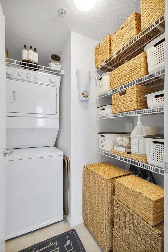 Dedicated laundry area featuring a stacked washer and dryer unit, ample wire shelving, and light-toned flooring