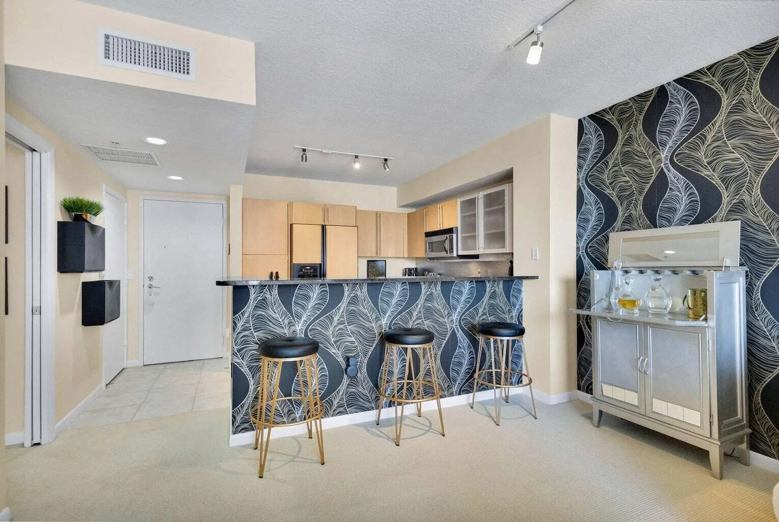 Kitchen bar with a patterned accent wall, recessed lighting, track lighting, light wood-finish cabinetry, and stainless steel appliances