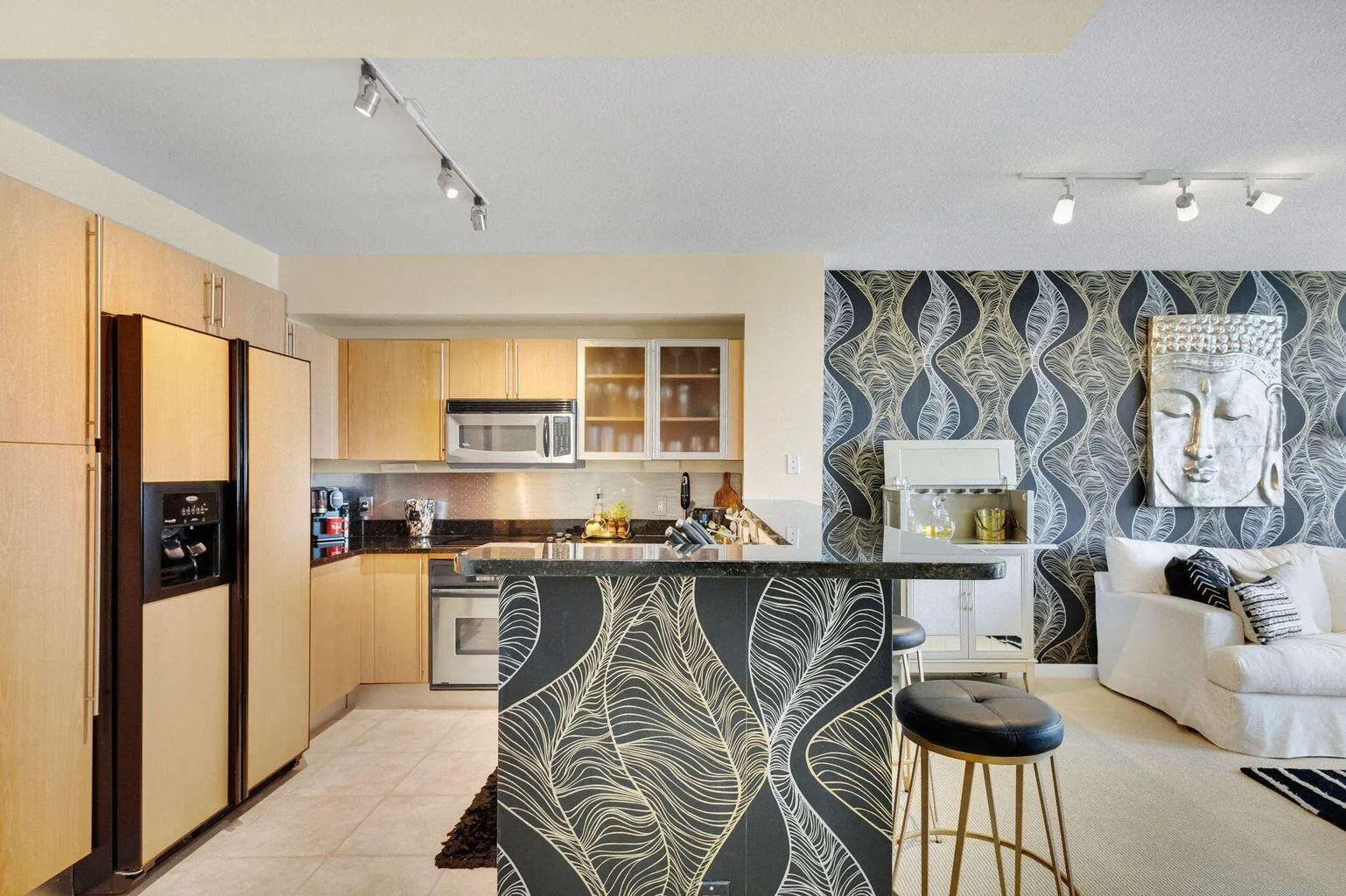 Open-concept living space with a kitchen featuring light wood-finish cabinetry and stainless steel appliances