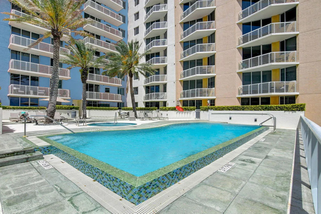 Resort-style pool area featuring a rectangular swimming pool with mosaic tile accents and an adjacent spa