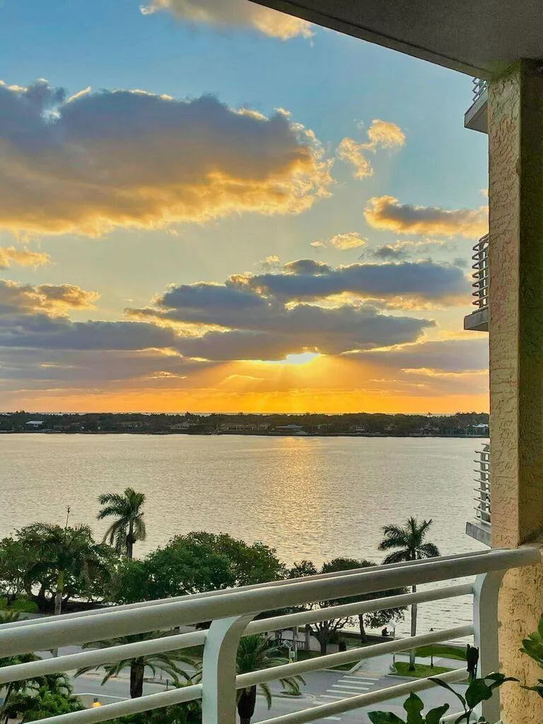 Waterfront balcony with white railings, offering an expansive water panorama and distant tree-lined shoreline
