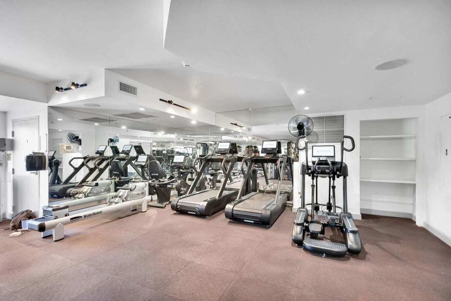 Fitness center featuring mirrored walls, recessed lighting, and built-in shelving