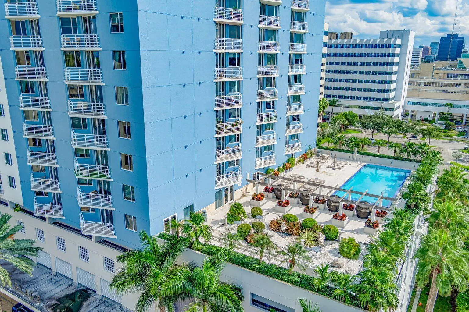 Rooftop amenity deck featuring a swimming pool, lounge areas with pergolas, and structured landscaping with palm trees