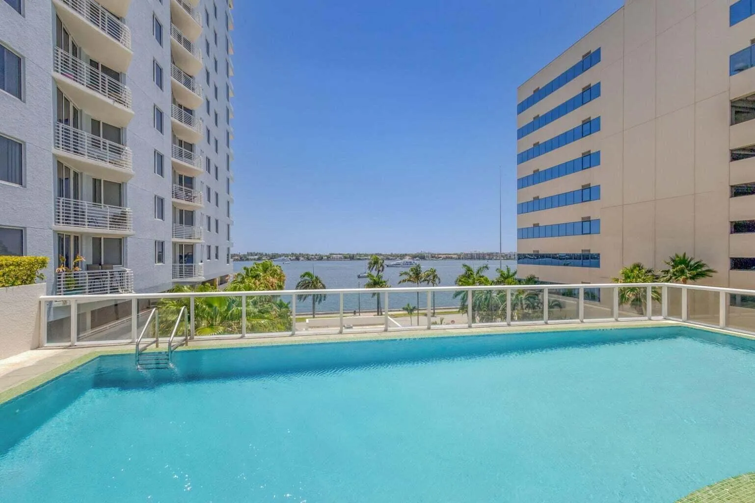 Outdoor swimming pool with clear water, glass perimeter railing, and integrated pool steps