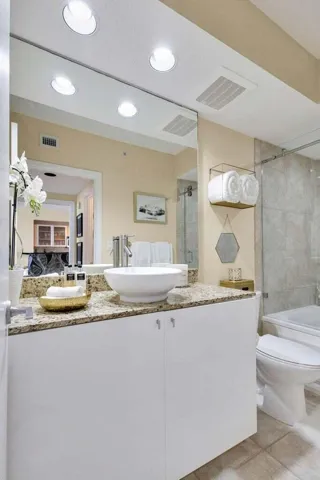 Modern vanity featuring a vessel sink, stone-finish countertop, and integrated storage cabinetry