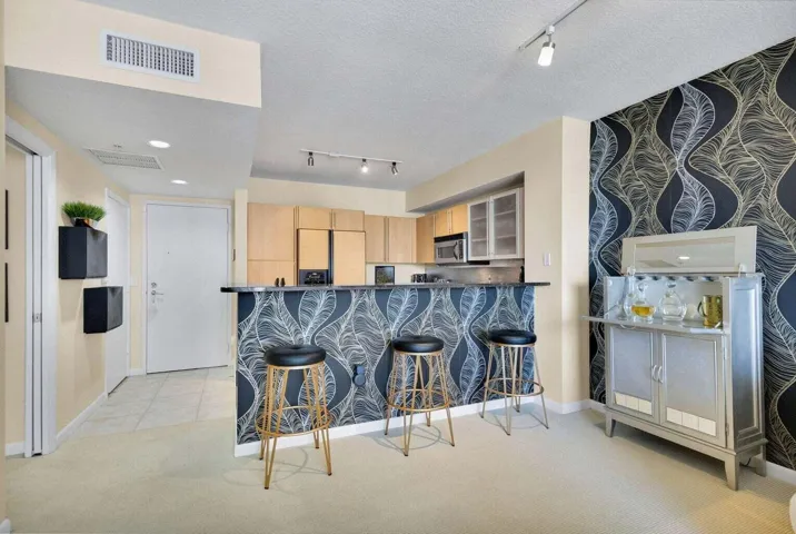 Kitchen bar with a patterned accent wall, recessed lighting, track lighting, light wood-finish cabinetry, and stainless steel appliances