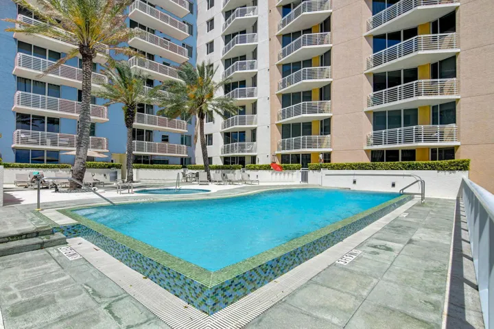 Resort-style pool area featuring a rectangular swimming pool with mosaic tile accents and an adjacent spa