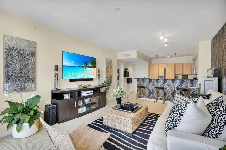 Open-concept living area featuring a kitchen pass-through with a patterned bar face and bar seating