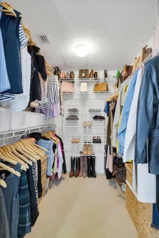 Spacious walk-in closet featuring built-in wire shelving, multiple hanging rods, and recessed lighting