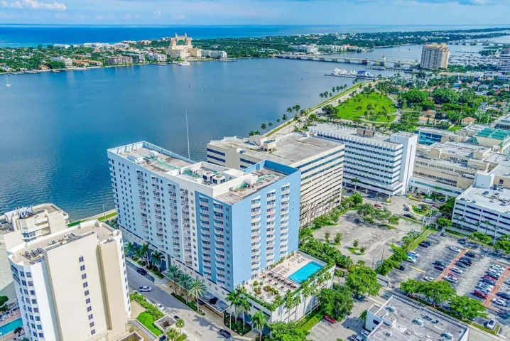 Waterfront high-rise building featuring a rooftop pool deck, multiple balconies, and integrated street-level commercial spaces