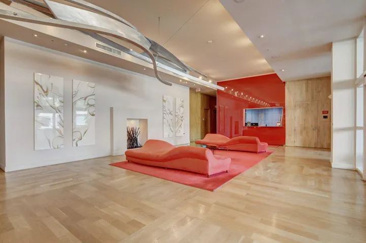 Contemporary lobby featuring light wood-finish flooring, recessed lighting, and a distinctive sculptural ceiling fixture