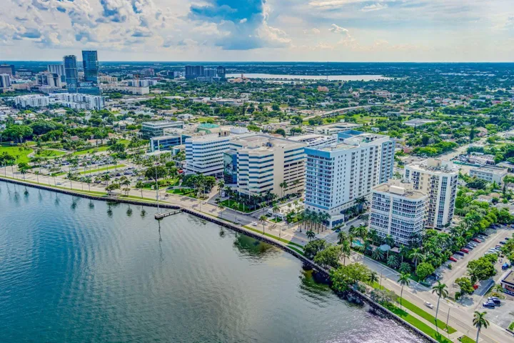 Waterfront property featuring multiple high-rise buildings, a marina with boat slips, and a tree-lined promenade