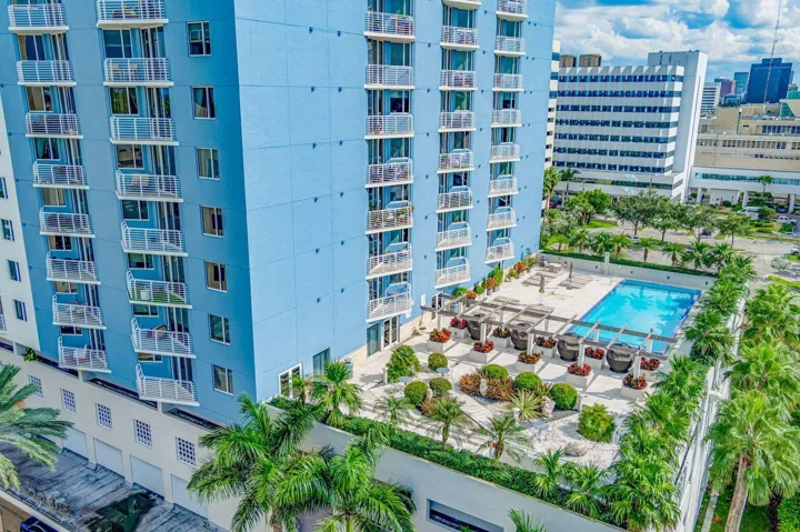 Rooftop amenity deck featuring a swimming pool, lounge areas with pergolas, and structured landscaping with palm trees