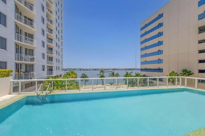 Outdoor swimming pool with clear water, glass perimeter railing, and integrated pool steps