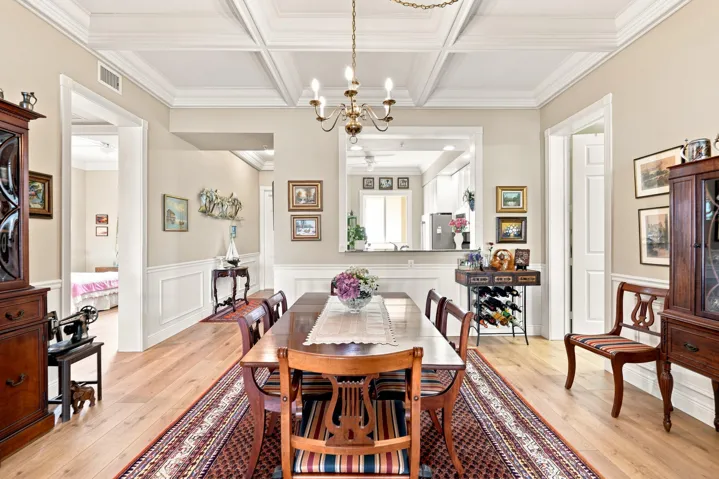 Spacious dining area with coffered ceilings and chandelier.