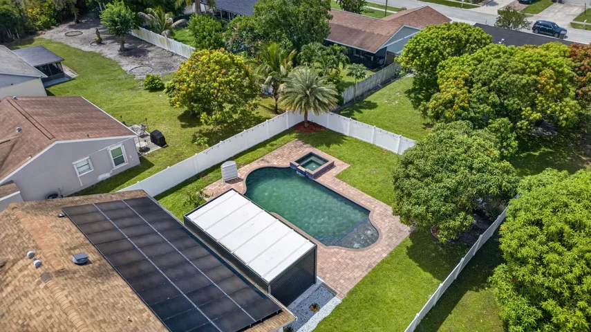 Backyard oasis featuring a swimming pool with integrated spa, paver patio, and mature landscaping