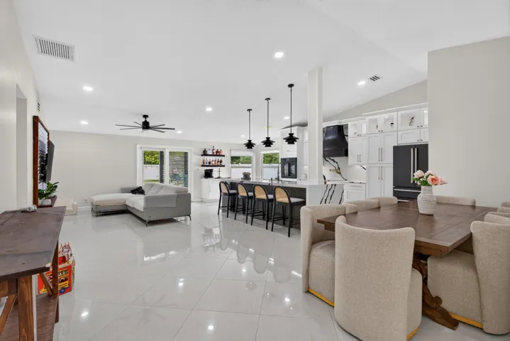 Open-concept living space featuring polished porcelain tile flooring throughout, recessed and pendant lighting, and seamless sightlines between the living area, dining space, and kitchen