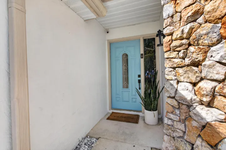 Stone veneer wall accenting a light blue entry door with decorative glass inserts and black hardware