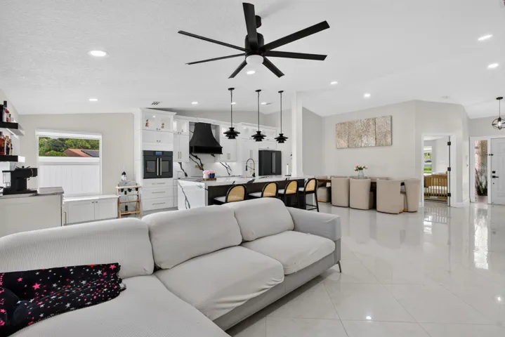 Spacious open-concept interior with large format tile flooring, recessed lighting, and a modern ceiling fan