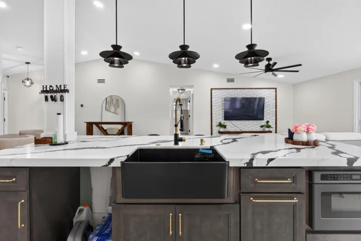Kitchen island with a large black farmhouse sink, quartz-finish countertop, and integrated microwave