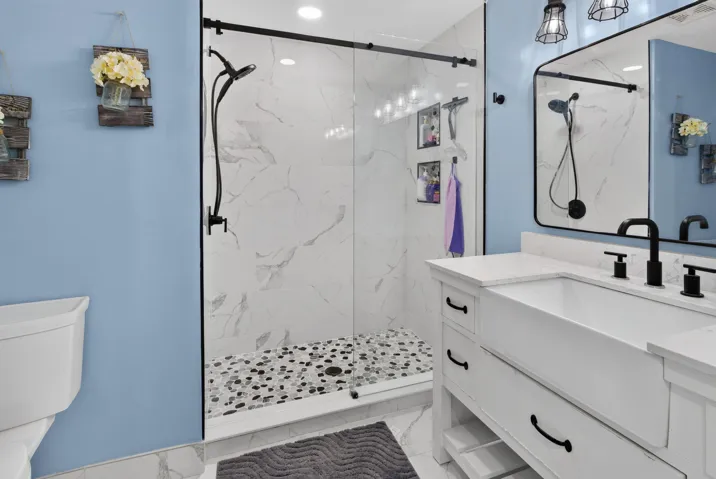 Shower enclosure featuring a sliding glass door and black hardware