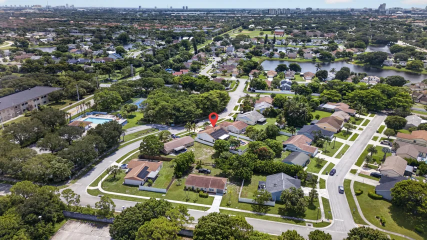 Aerial perspective showcasing a residential neighborhood with mature trees and a distant city skyline