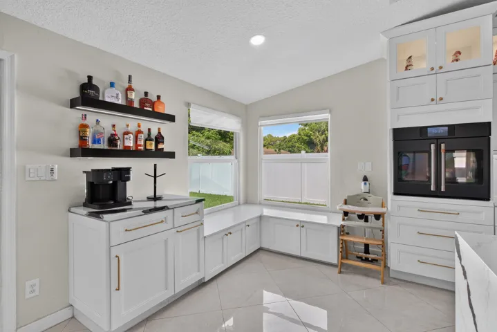 Integrated kitchen area featuring white cabinetry, a built-in double oven, and a window seat with storage