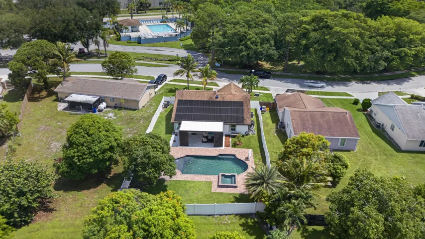 Residential property featuring an in-ground swimming pool with an integrated spa, an expansive paved pool deck, and a fenced backyard