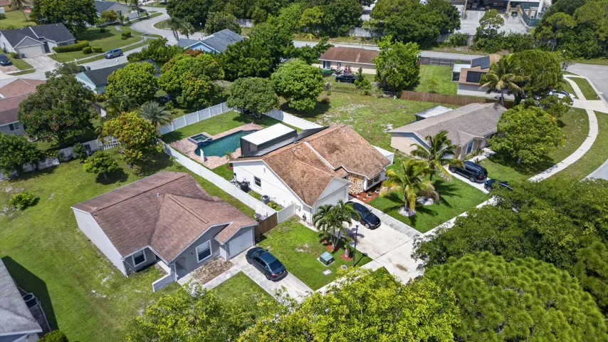 Aerial perspective showcasing a single-story residence with a swimming pool and hot tub, surrounded by mature trees