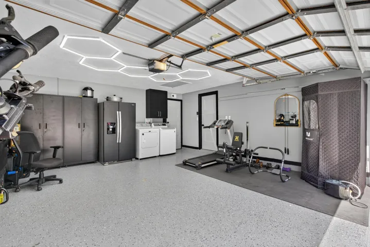 Concrete flooring with a speckled finish, hexagonal ceiling lighting, and a white paneled garage door