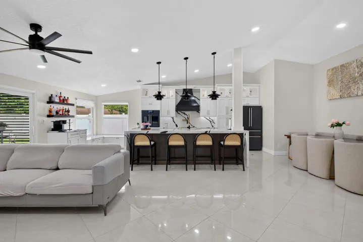 Spacious open-concept interior featuring light gray tile flooring, a vaulted ceiling, and recessed lighting