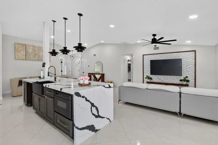 Kitchen island featuring a waterfall countertop with black veining, an undermount sink, and integrated appliances