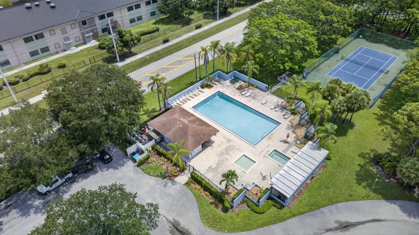 Community recreation area featuring a large swimming pool, two spas, a covered cabana, and a tennis court