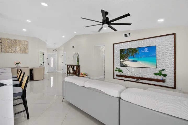 Spacious living area featuring vaulted ceilings, recessed lighting, and large format tile flooring