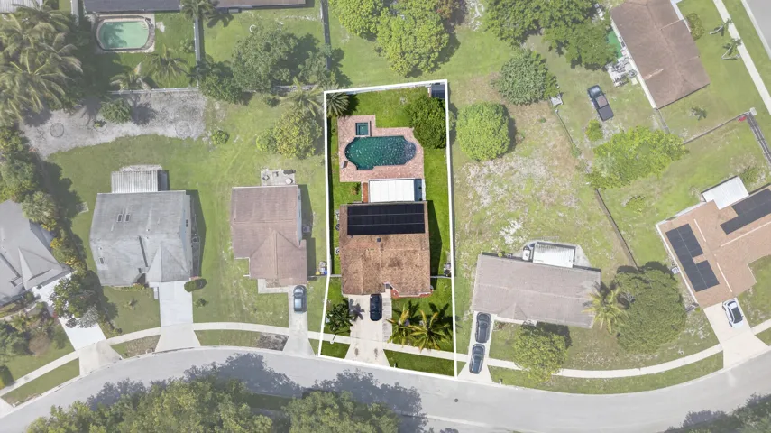 Aerial view showcasing a rectangular property featuring a private pool and spa, a spacious rear lawn, and mature landscaping